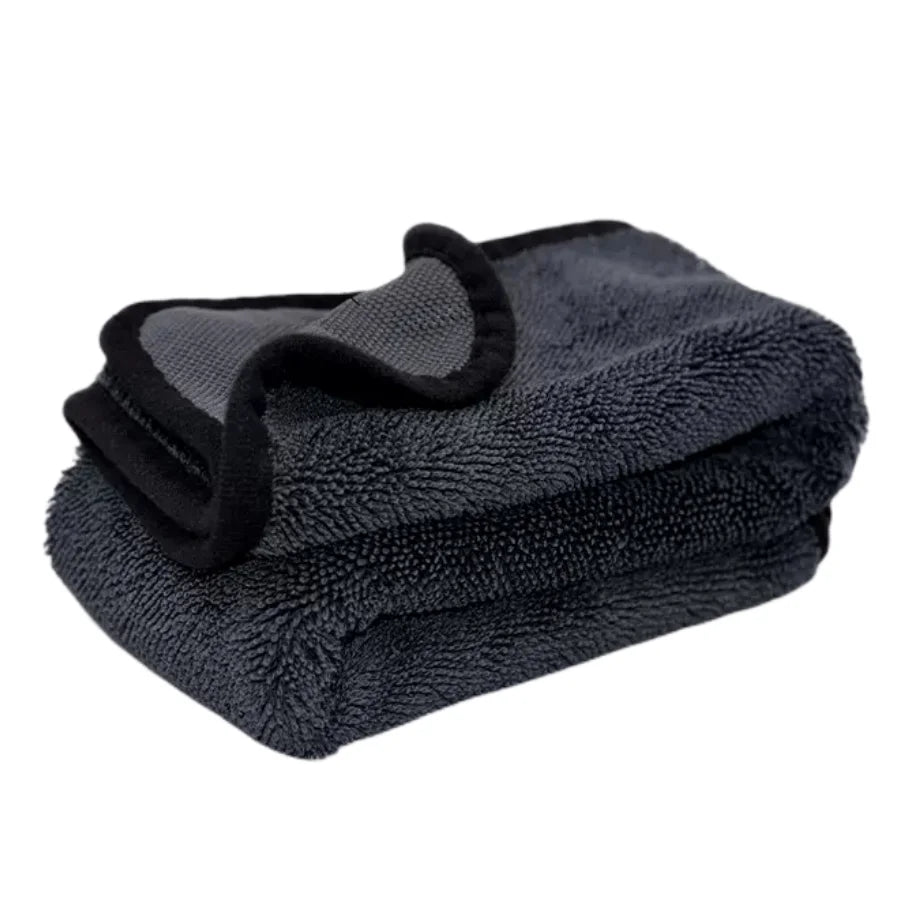 Folded dark gray towel with a black strap on a white background