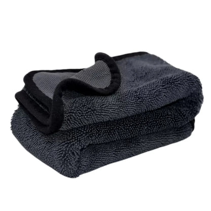 Folded dark gray towel with a black strap on a white background
